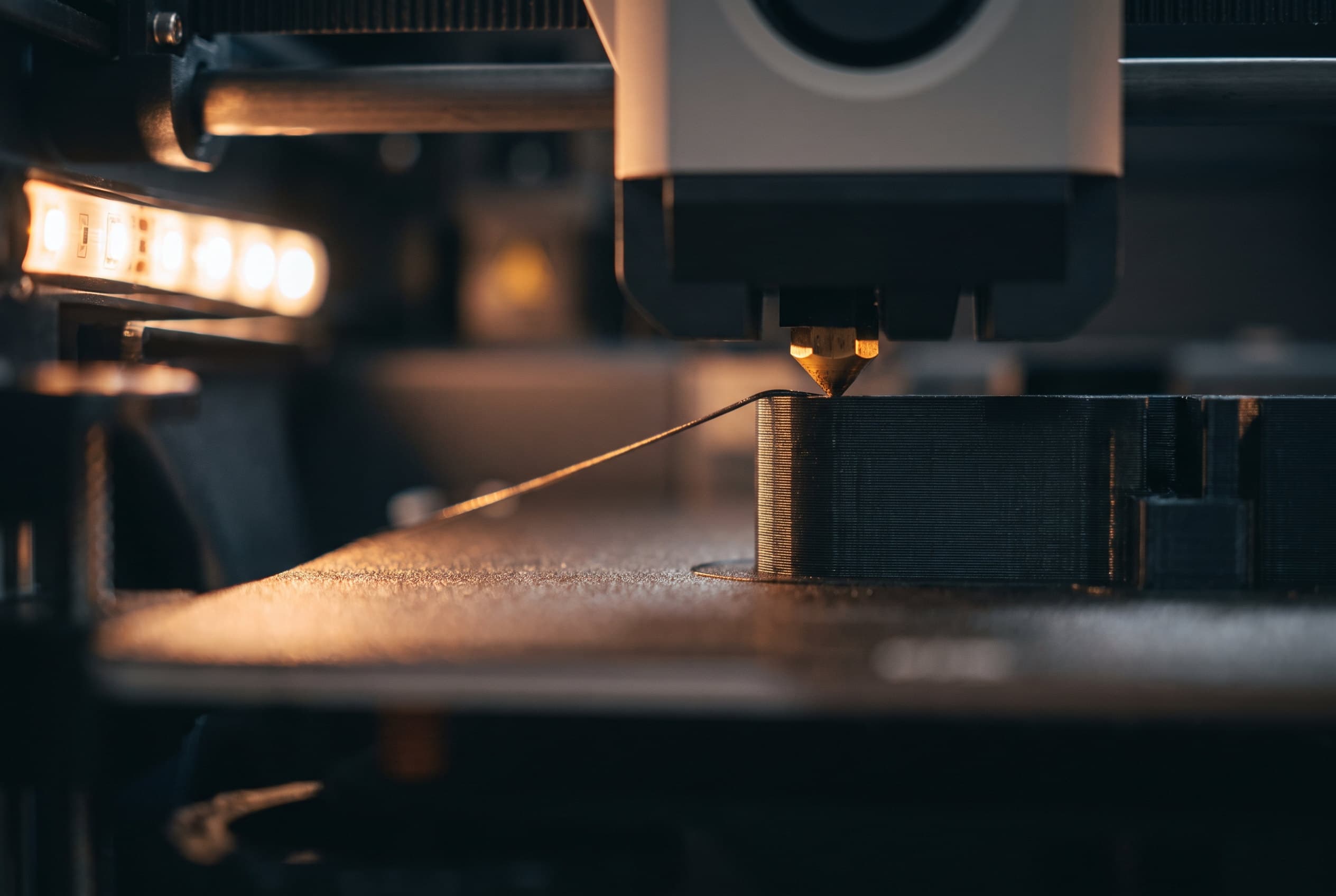 Düse eines 3D-Druckers, die eine schwarze technische Kunststoffschicht auflegt